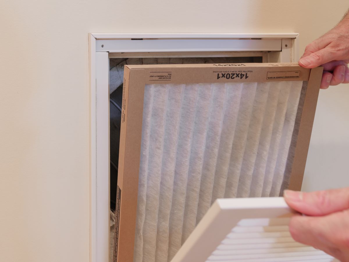 HVAC service technician replacing dirty indoor air filter in residential heating and air conditioning system