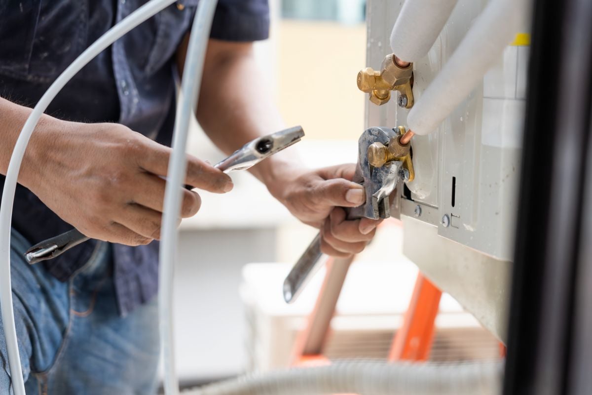 HVAC Technician Using Wrench to Connect AC Pipes