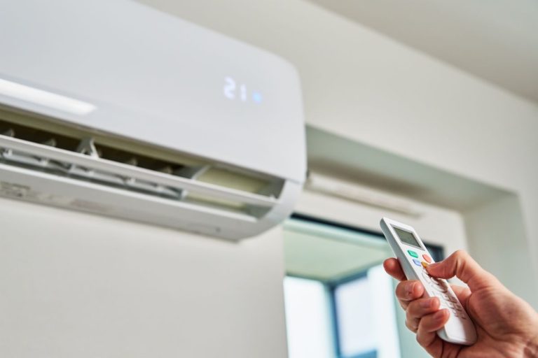 Hand adjusting temperature on air conditioner with remote control